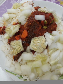 A picture of White rice with stew,cucumber and carrots.