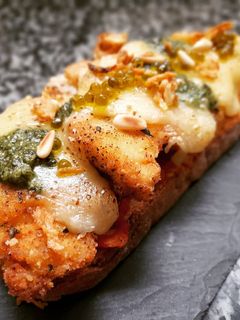Una foto de Milanesa de pollo al pesto en torrada
