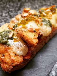 Una foto de Milanesa de pollo al pesto en torrada