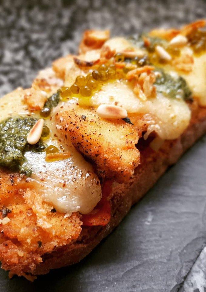 Una foto de Milanesa de pollo al pesto en torrada