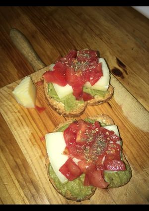 Una foto de Tostadas con guacamole, queso y tomate