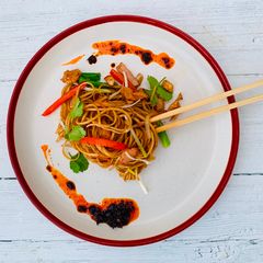 A picture of Egg noodles stir-fried with chicken and bacon.