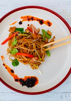 A picture of Egg noodles stir-fried with chicken and bacon.