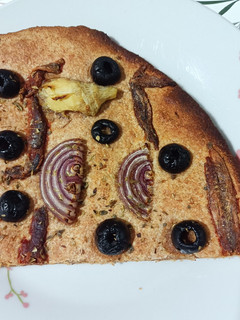 Una foto de Coca de alcachofas, cebolla roja, anchoas y aceitunas negras