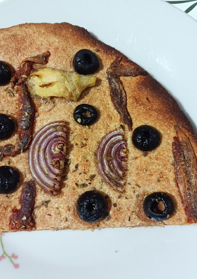 Una foto de Coca de alcachofas, cebolla roja, anchoas y aceitunas negras