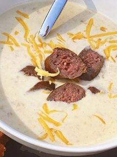 A picture of Oktoberfest Beer and Smoked Cheddar Soup with Fullblood Wagyu Beef Bratwurst.