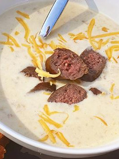 A picture of Oktoberfest Beer and Smoked Cheddar Soup with Fullblood Wagyu Beef Bratwurst.