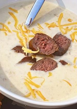 A picture of Oktoberfest Beer and Smoked Cheddar Soup with Fullblood Wagyu Beef Bratwurst.