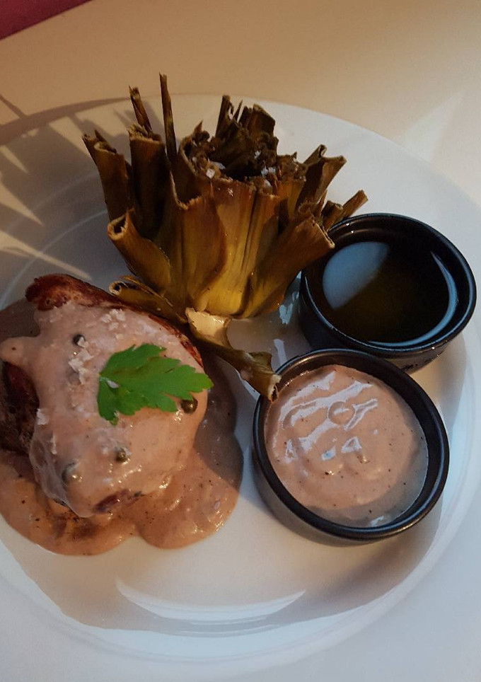 Una foto de Solomillo a la pimienta verde con aroma de tinto y alcachofas