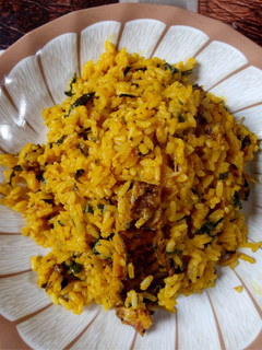 A picture of Local Jellof Rice With Palm Oil, Scent leaf and Dry Fish.