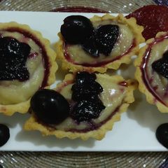 A picture of Sweet tarts fill with black grapes crush,& custard.