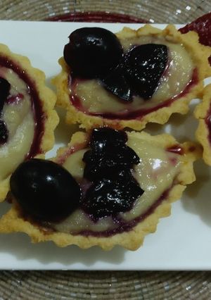 A picture of Sweet tarts fill with black grapes crush,& custard.