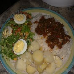 A picture of White rice and stew with boiled potatoes and salad.