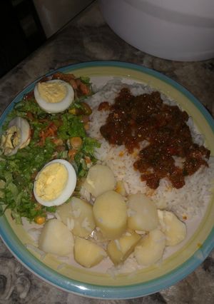 A picture of White rice and stew with boiled potatoes and salad.