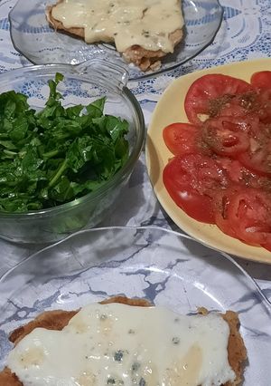 Una foto de Milanesas al horno con mozzarella y queso azul - rúcula y tomates
