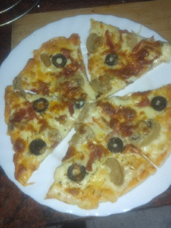 Una foto de Pizza de jamón serrano, champiñones y aceitunas negras