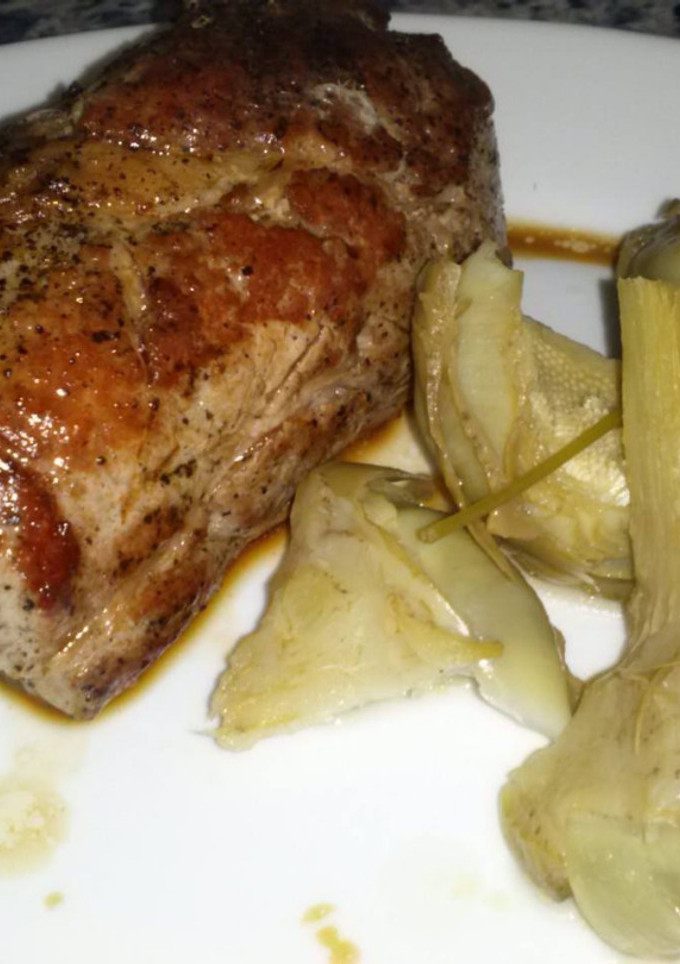 Una foto de Solomillo de cerdo en su jugo con alcachofas tiernas al limón