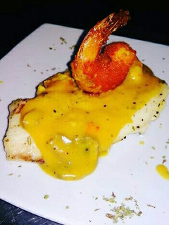 Una foto de Pescado Blanco en Crema de Champiñones coronado con Camarón Crispy