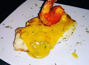 Una foto de Pescado Blanco en Crema de Champiñones coronado con Camarón Crispy
