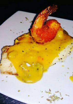 Una foto de Pescado Blanco en Crema de Champiñones coronado con Camarón Crispy
