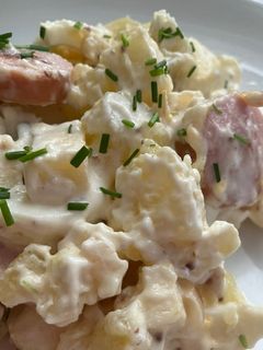 Una foto de Ensalada alemana (kartoffelsalat) con salchichas de queso ahumadas (Bockwurst)