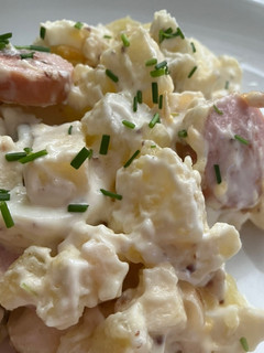 Una foto de Ensalada alemana (kartoffelsalat) con salchichas de queso ahumadas (Bockwurst)