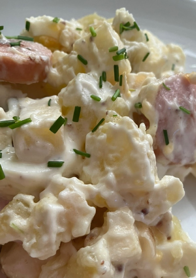 Una foto de Ensalada alemana (kartoffelsalat) con salchichas de queso ahumadas (Bockwurst)