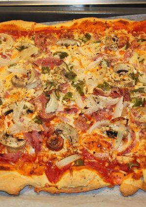 Una foto de Pizza casera de pollo con salsa barbacoa y champiñones