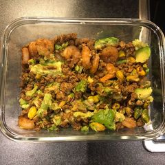 A picture of King prawns on lentils and pistachios with avocado.