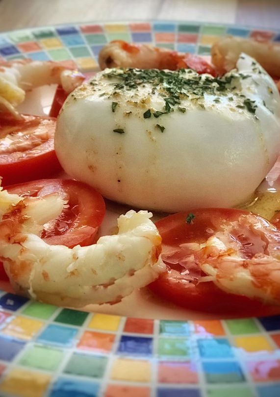 Una foto de Burrata con tomate y langostinos en su salsa