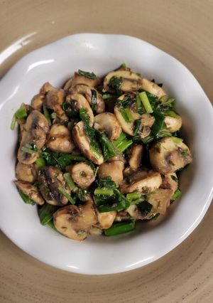 A picture of Mushrooms with green onions and parsley.