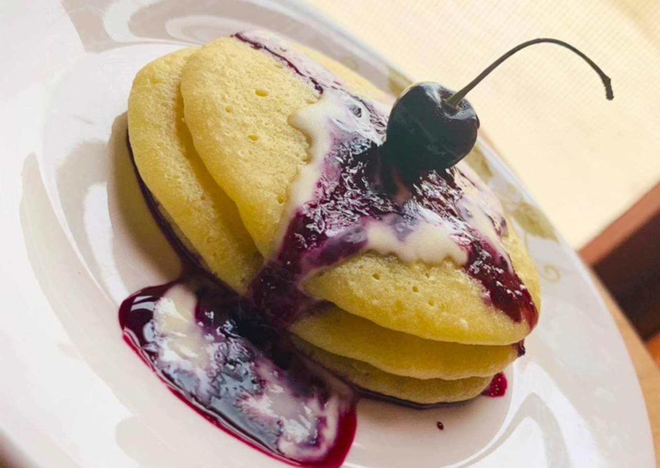 Pancakes served with cherry sauce and cream cheese