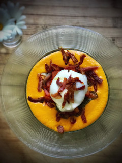 Una foto de Burrata con crujiente de jamón ibérico sobre salmorejo y pesto de albahaca