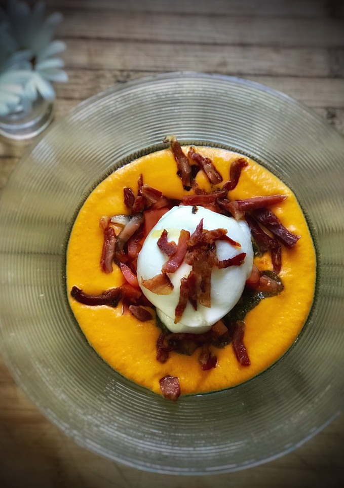 Una foto de Burrata con crujiente de jamón ibérico sobre salmorejo y pesto de albahaca