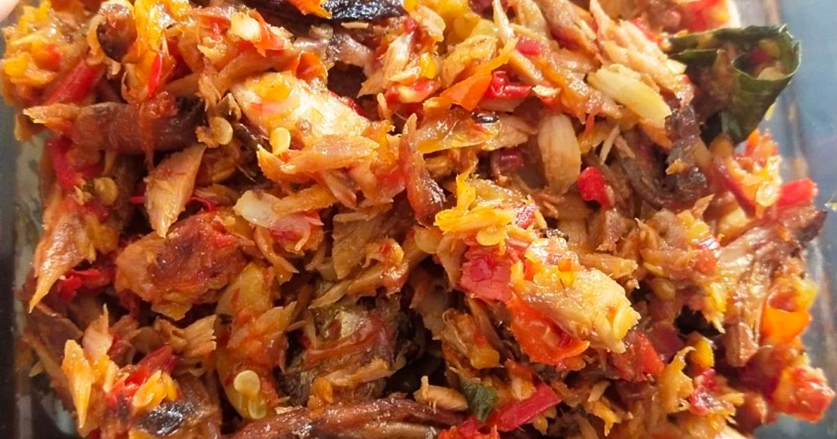 Sambal ikan dengan warna merah oranye kaya bumbu tersaji dalam mangkuk kecil dengan daun segar di sekitarnya
