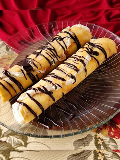 Una foto de 🫔Panqueques rellenos de manzana, pasas y crema, bañados con salsa de chocolate🫔 Canelones dulces