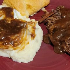 A picture of Beef roast with mashed potatoes and beef gravy.