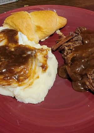 A picture of Beef roast with mashed potatoes and beef gravy.