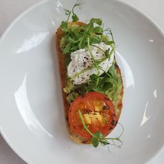 Soft Poached egg smashed avocado grilled tomato on sourdough A picture of Soft Poached egg smashed avocado grilled tomato on sourdough.