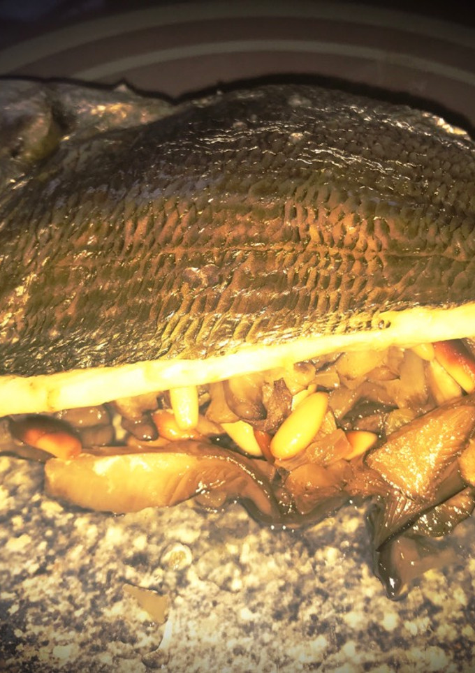 Una foto de Lomo de dorada al horno sobre cama de setas y piñones