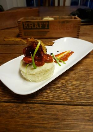 A picture of Sausages in tomato reduction w/ white potato mousseline and chip.