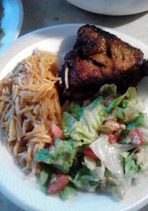 A picture of fried chicken with fideo and salad.
