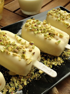 Una foto de Helado de mango, chocolate blanco y pistachos