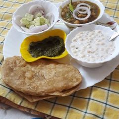 A picture of Bhaturas with white chana and boondis raita.
