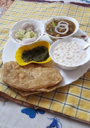 A picture of Bhaturas with white chana and boondis raita.