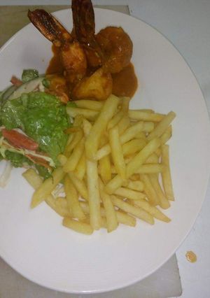 A picture of Jumbo prawns in tomatoes sauce with chips.