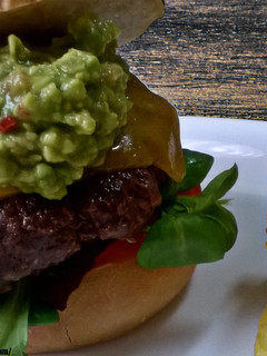 Una foto de Hamburguesa de ternera con guacamole, queso cheddar, y vegetales