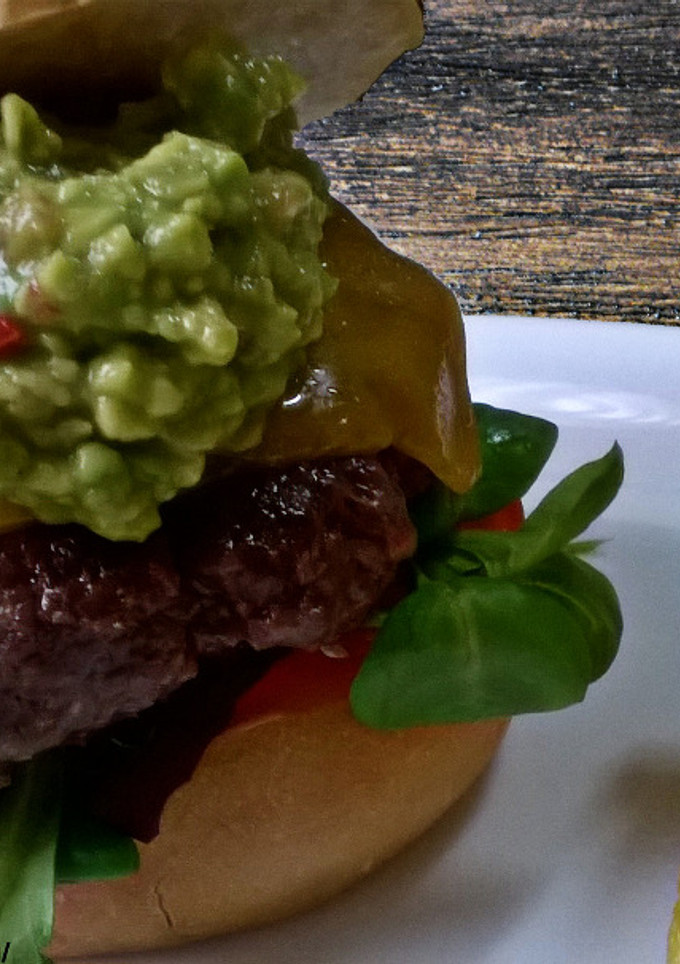 Una foto de Hamburguesa de ternera con guacamole, queso cheddar, y vegetales