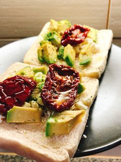 Una foto de Tostada de aguacate, queso feta y tomate seco