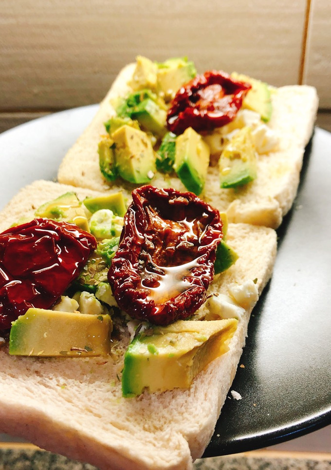 Una foto de Tostada de aguacate, queso feta y tomate seco
